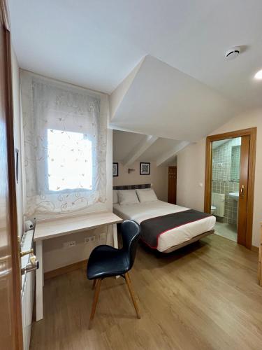a bedroom with a bed and a chair and a window at Hostal la Colmena in Ávila
