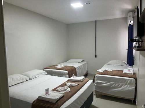 a room with three beds in a room at Hotel Moriah in Umuarama