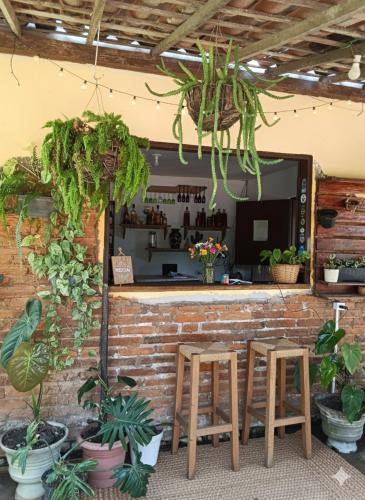 a bar with two wooden stools and plants at Pousada Mandacaru, próximo a Usina de Arte in Campestre