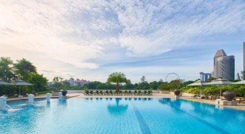 a large swimming pool with chairs and buildings in the background at PARKROYAL on Beach Road, Singapore in Singapore