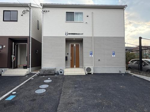 a parking lot in front of a house at 熊本熊猫基地セミコンハブ Kumamoto Panda Base Semicon Hub in Ozu