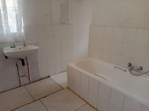 a bathroom with a sink and a bath tub and a sink at Happy Guest House in Mahikeng