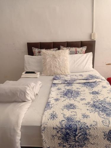 a large bed with white and blue sheets and pillows at Happy Guest House in Mahikeng