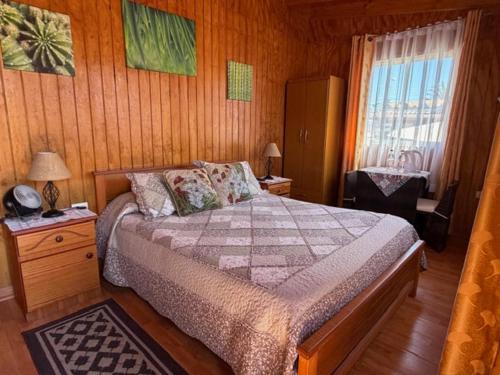 a bedroom with a bed in a wooden room at Hotel Cabañas Caribe in Los Vilos