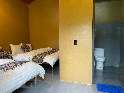 two beds in a room with a toilet at Km 0 home Du Già in Muong Cha