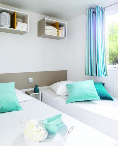 two beds in a room with a tray on a table at Mobilehome Super Mercure 2 Bedrooms Comfort Camping Scheldeoord in Baarland