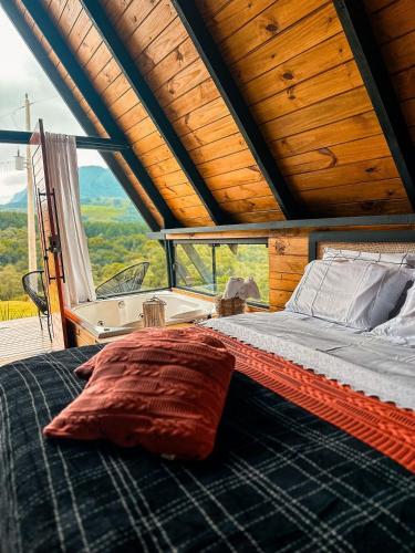 a bed in a room with a large window at Refúgio Mirante da Montanha in Alfredo Wagner