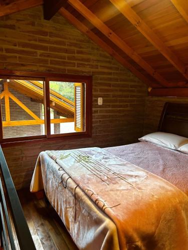 a bed in a wooden room with a window at Villetta Gramado Siena in Gramado