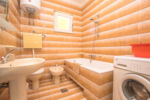 a bathroom with a sink toilet and a washing machine at Apartmani Jurin in Primošten