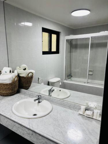 a bathroom with two sinks and a large mirror at Hotel Villa El Descanso Express in Curicó