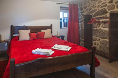 a bedroom with a red bed with towels on it at Casa da Cuca in Campo do Gerês