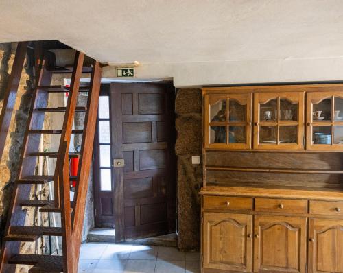 a staircase leading to a kitchen with wooden cabinets at Casa dos Cobertos in Terras de Bouro