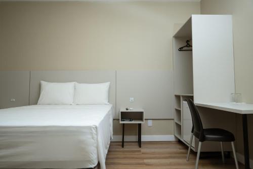 a bedroom with a bed and a desk and a chair at Hotel Equinócios Express in Barcarena