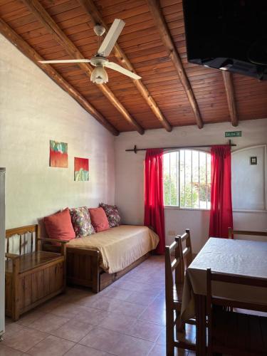 a bedroom with a bed with red curtains and a table at Complejo Alto Paraiso in Villa Cura Brochero