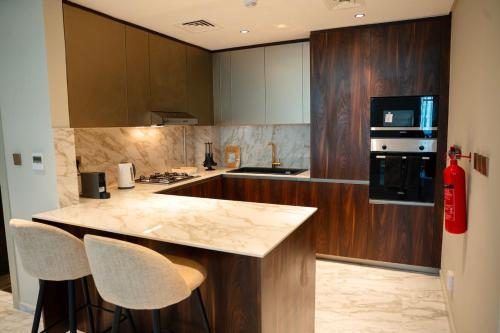 a kitchen with a counter and two bar stools at Italian-Design 2BR l Large Private Terrace l Near Marina & Expo City in Dubai