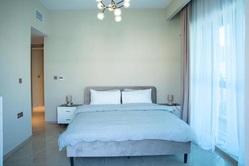a white bedroom with a large bed and a chandelier at Italian-Design 2BR l Large Private Terrace l Near Marina & Expo City in Dubai