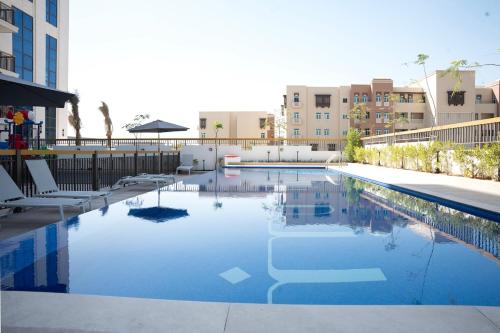 a large swimming pool with chairs and buildings in the background at Italian-Design 2BR l Large Private Terrace l Near Marina & Expo City in Dubai