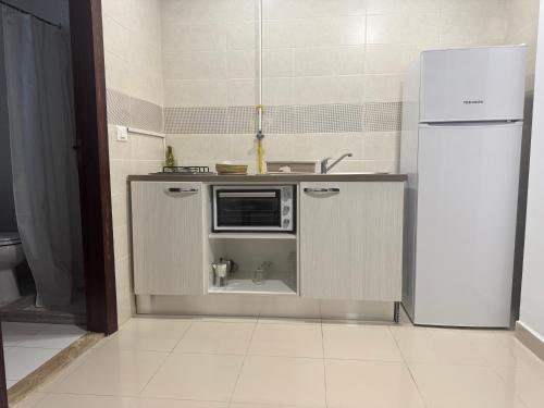 a kitchen with a microwave and a refrigerator at Le charbon élégant in Bin Rhilouf