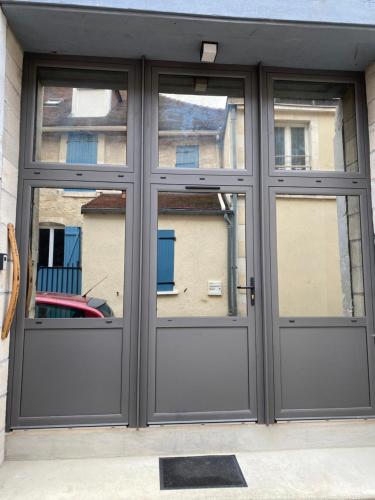 a garage door with three windows in front of a building at Le Merrain gîte plein coeur de Chablis in Chablis