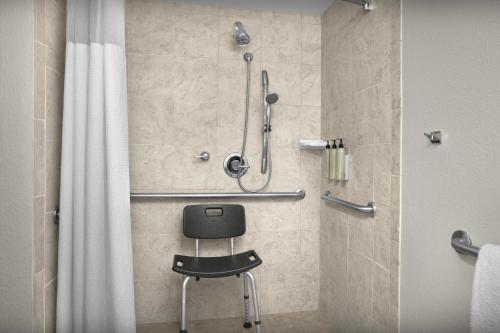 a shower with a black chair in a bathroom at Courtyard by Marriott Waco in Waco