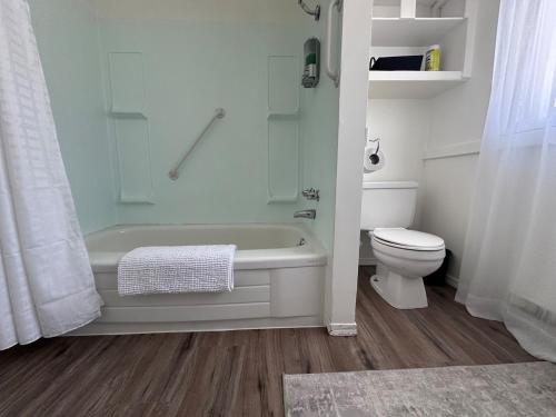 a white bathroom with a tub and a toilet at Texada Hunter Hiker friendly suite in Vananda