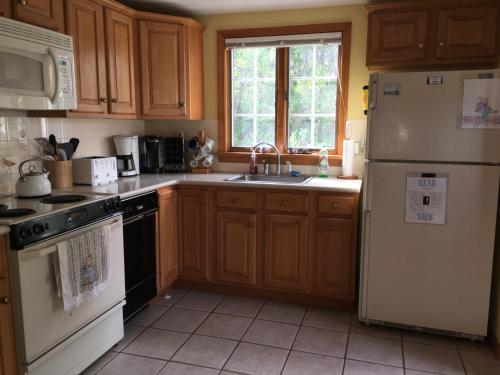 a kitchen with wooden cabinets and a white refrigerator at Bayside Bliss in Dennis