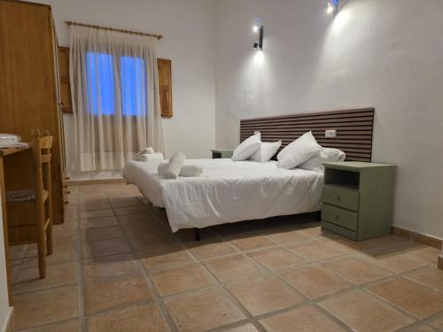 a bedroom with a large white bed and a night stand at La Cilla Moratalla in Moratalla