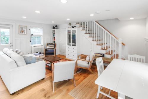 a living room with white furniture and a staircase at Harbor Breeze Townhouse in Provincetown