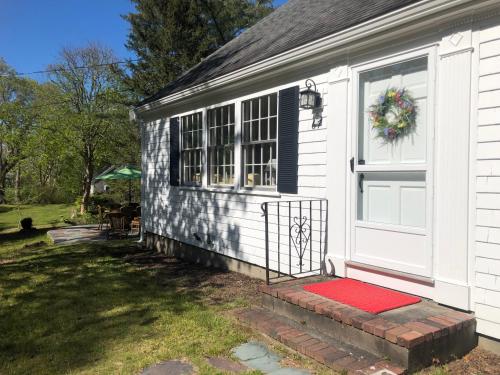 a white house with a red door and a window at Sunny Days in Brewster