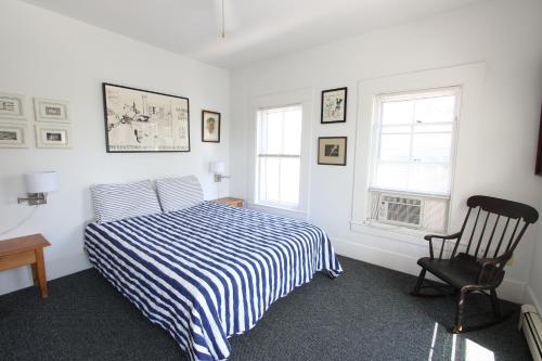 a bedroom with a bed and a chair and two windows at High Tide Upper Level in Provincetown