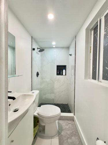 a white bathroom with a toilet and a sink at Cozy Private House near Miami Airport - Free parking - 01 in Miami