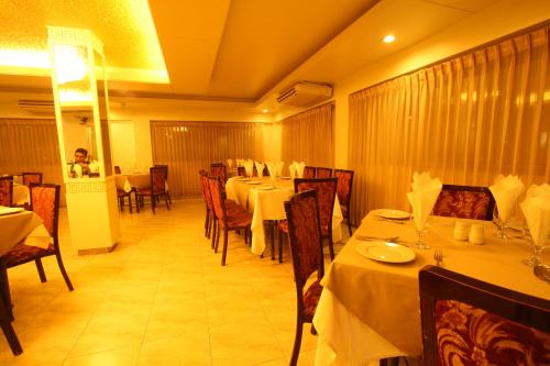 a dining room with tables and chairs with white tablecloths at Hotel Ornate in Dhaka
