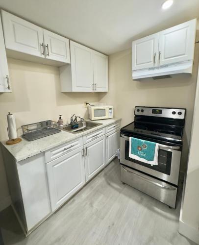 a kitchen with white cabinets and a stove top oven at Cozy Private House near Miami Airport - Free parking - 01 in Miami