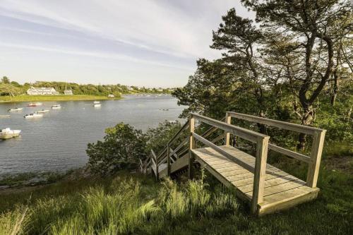 a wooden bench sitting on the side of a river at Aweigh We Go in Chatham