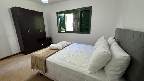 a bedroom with a bed with white sheets and pillows at Apto 2D ensolarado, sacada e garagem, centro in Nova Petrópolis