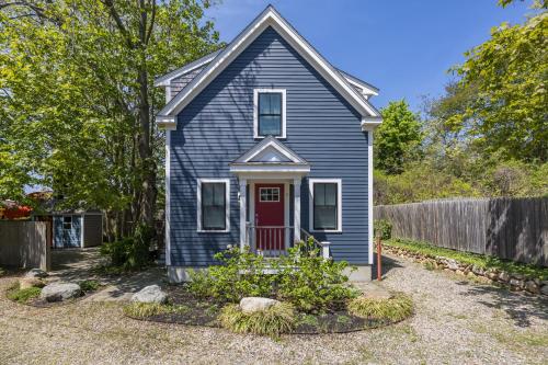 a blue house with a red door in a yard at Cod Hollow in Provincetown