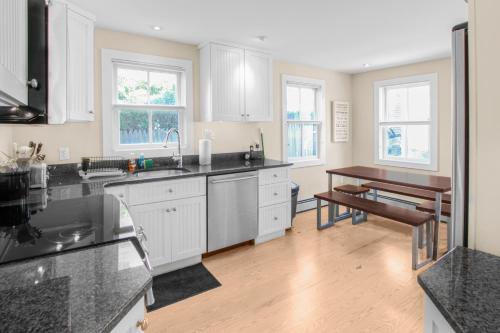 a kitchen with white cabinets and a wooden floor at Harbor Hideaway in Provincetown
