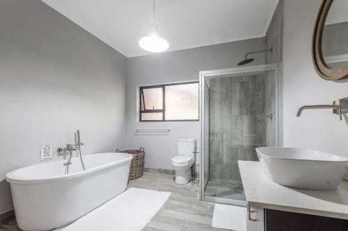 a bathroom with a tub and a sink and a toilet at Honeysuckle in Tzaneen
