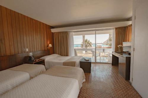 a hotel room with three beds and a balcony at Hotel Arica in Arica