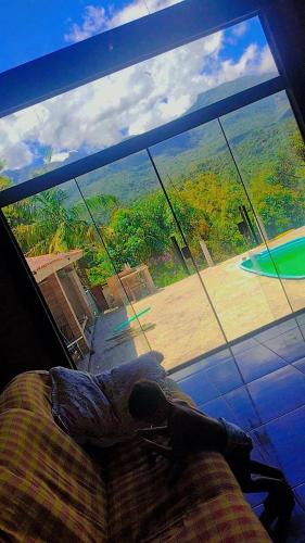 a bedroom with a large window looking out at a yard at Serra mineira in Resende