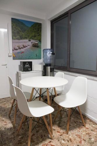 una mesa y sillas blancas en una habitación con ventana en Villa 2VB, en Shkodër