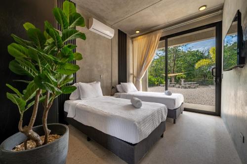 a bedroom with two beds and a potted plant at Nelblu Flamingo Suites in Playa Flamingo