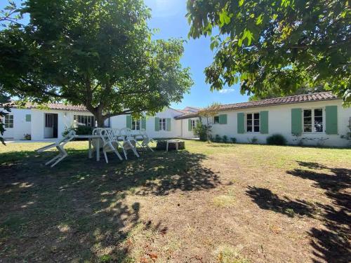 a house with a tree and chairs in the yard at La Villa du Clocher in Saint-Clément-des-Baleines