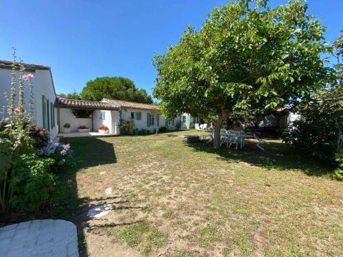 a yard with a tree and a house at La Villa du Clocher in Saint-Clément-des-Baleines