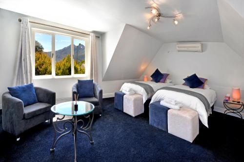 1 dormitorio con 2 camas, mesa y sillas en Lemon Tree Cottage Self Catering en Franschhoek