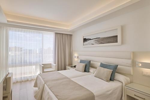 a hotel room with a bed and a window at Hotel Argos Ibiza in Talamanca