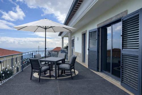 a patio with a table and chairs and an umbrella at Villa Vieira Ocean View in Gaula