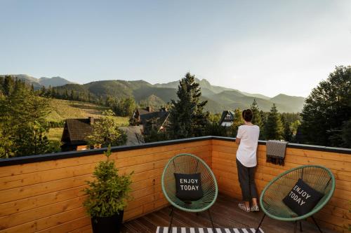 a person standing on a balcony looking at the mountains at Villa 11 Folk & Design in Zakopane