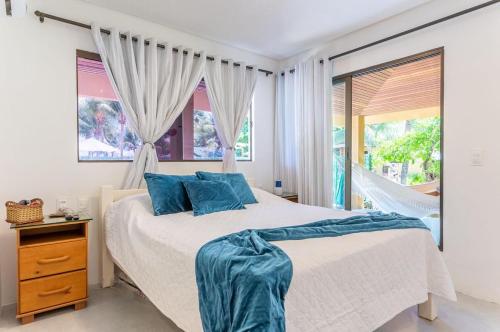a bedroom with a bed with blue pillows and a window at Chales Maragogi in Maragogi