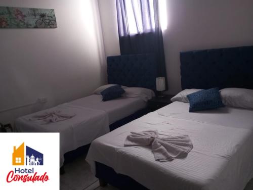 two beds in a hotel room with towels on them at HOTEL CONSULADO Junto al Consulado de Venezuela in Cúcuta